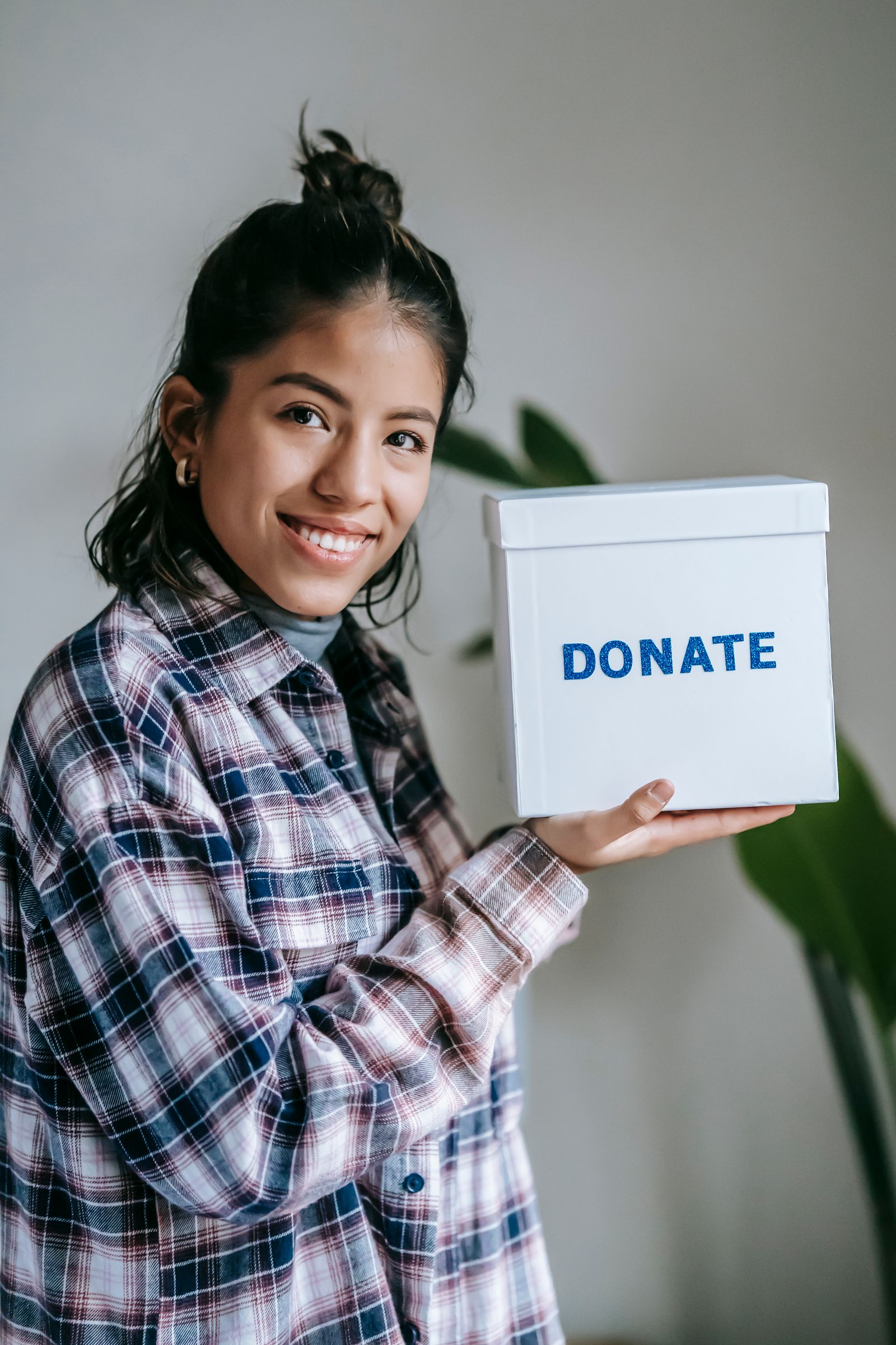 A smiling woman holding a white box marked Donate