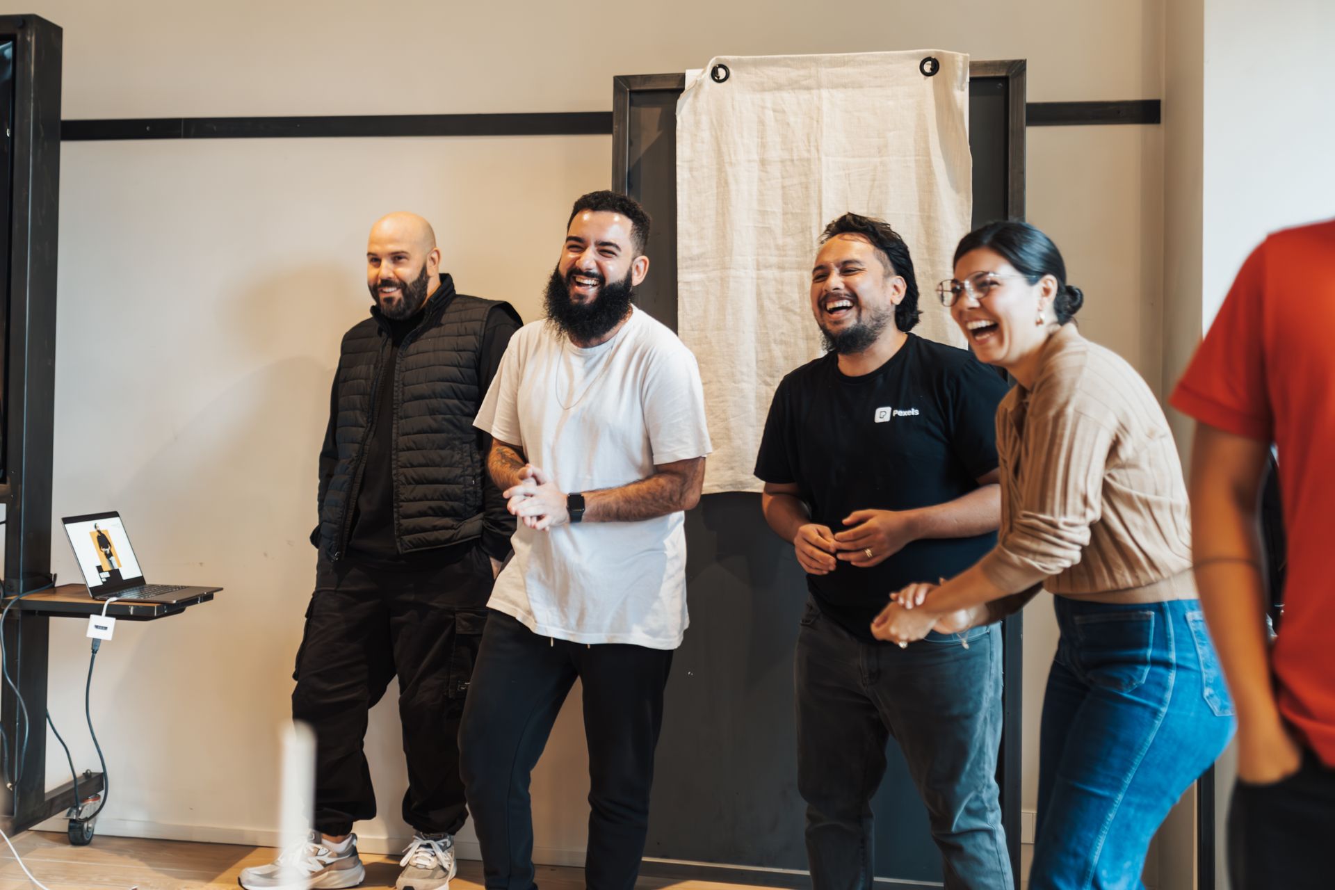 A group of friends standing together and laughing in a bright room