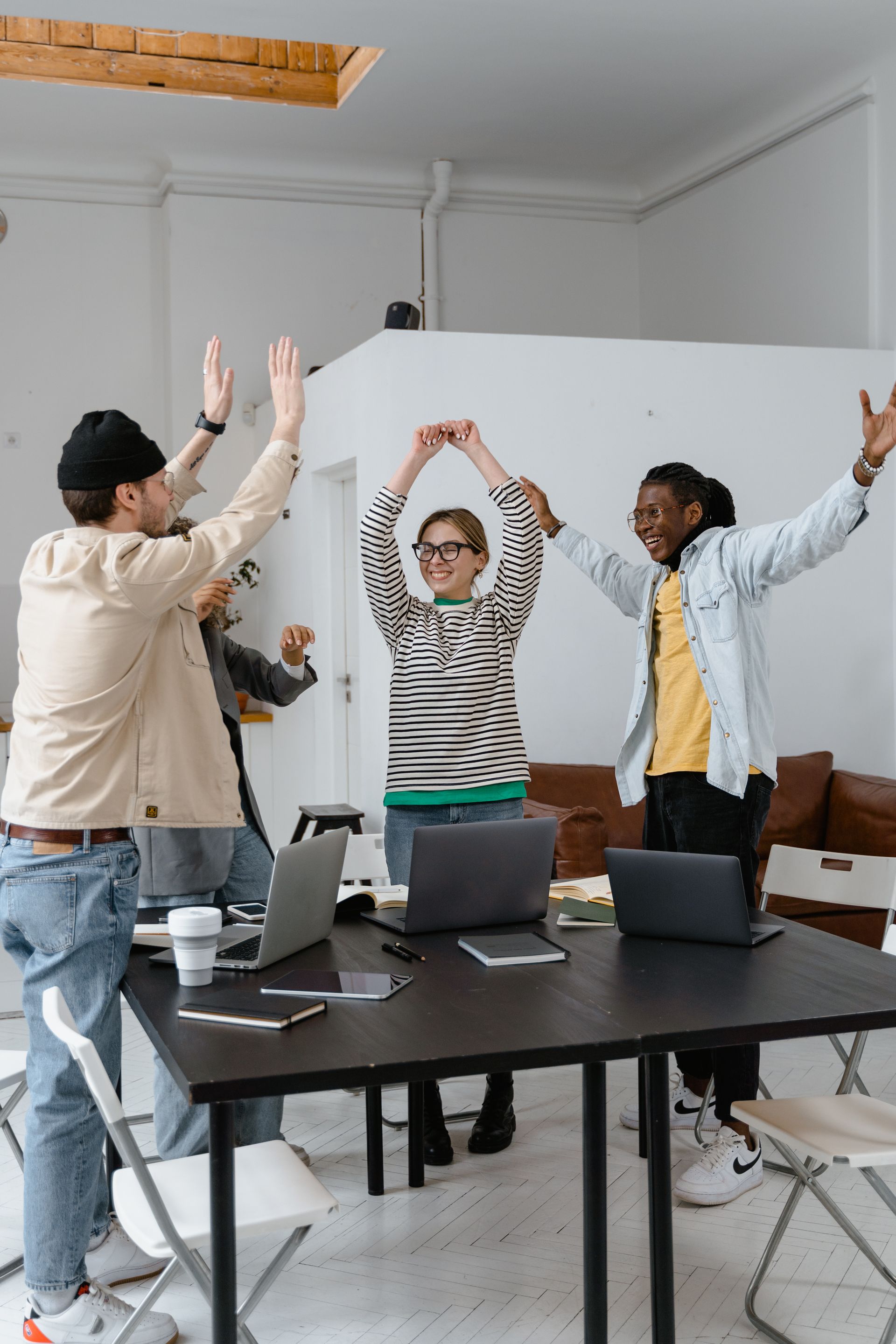 A team celebrating with their arms raised in a bright studio
