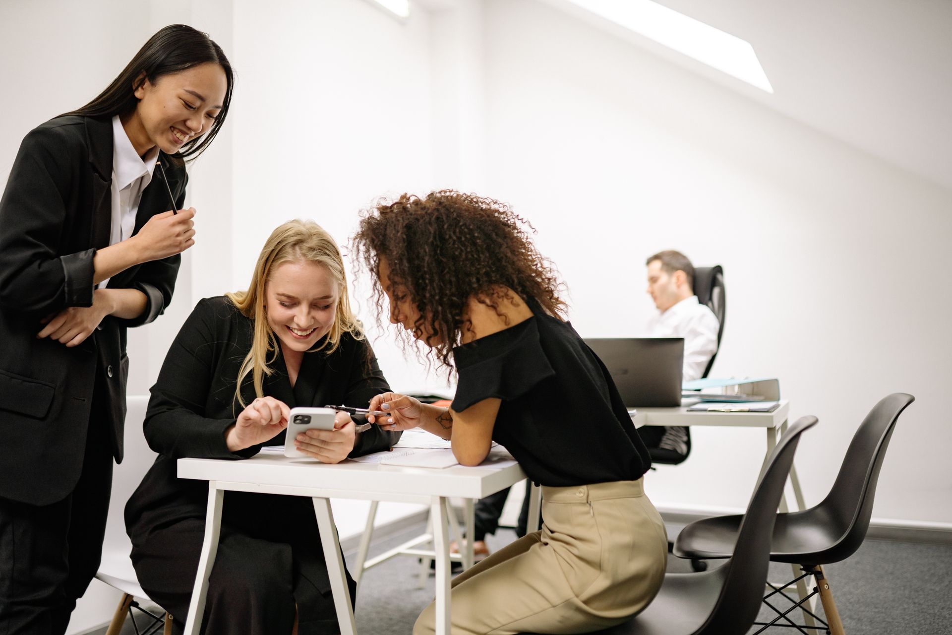 Three colleagues smiling and looking at a phone together