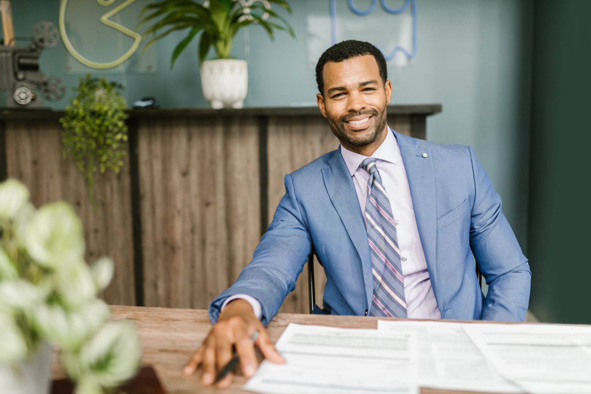 A smiling accountant in a blue suit seated at a desk with paperwork