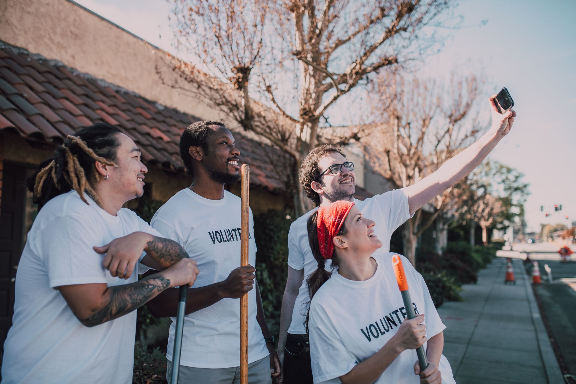 Four smiling volunteers taking a selfie together on a sunny street